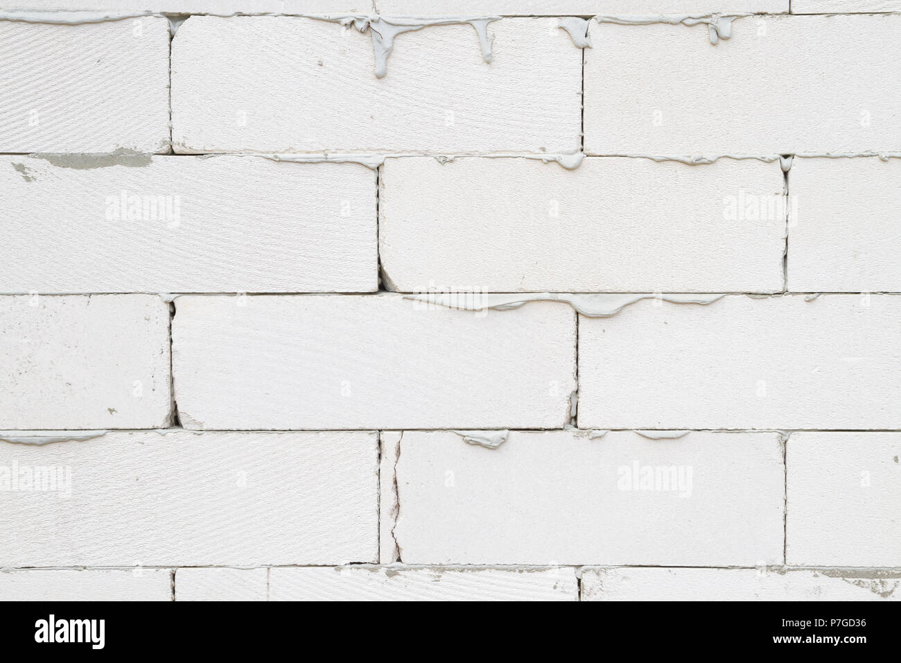 The wall of the house is made of light gray brick with stains of cement