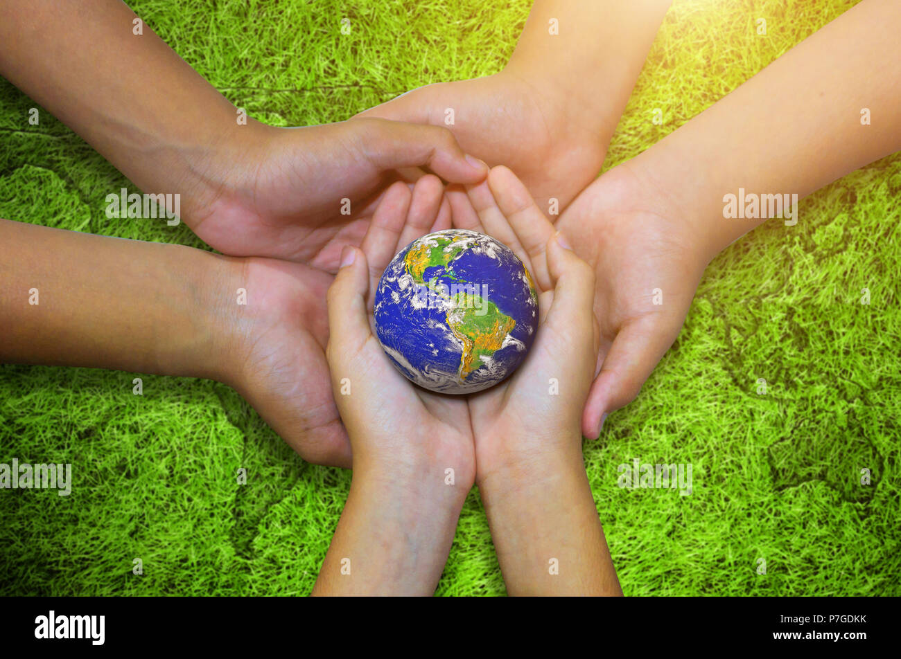 Earth planet in asian Children hand on green grass background. - Elements of this image furnished by NASA Stock Photo