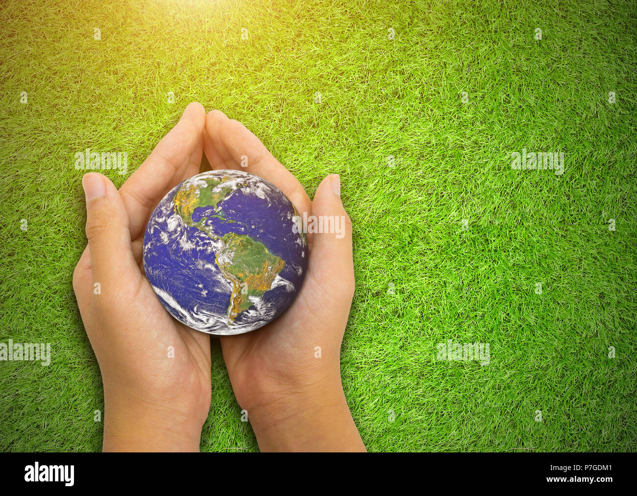 Earth planet in asian Children hand on green grass background. - Elements of this image furnished by NASA Stock Photo