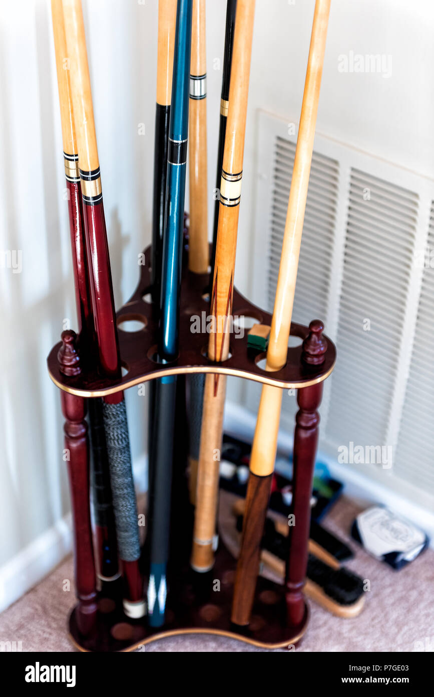 Closeup of wooden mahogany finish billiard pool cue sticks standing stand, rack, holder in living room home with chalk, brush, cues Stock Photo