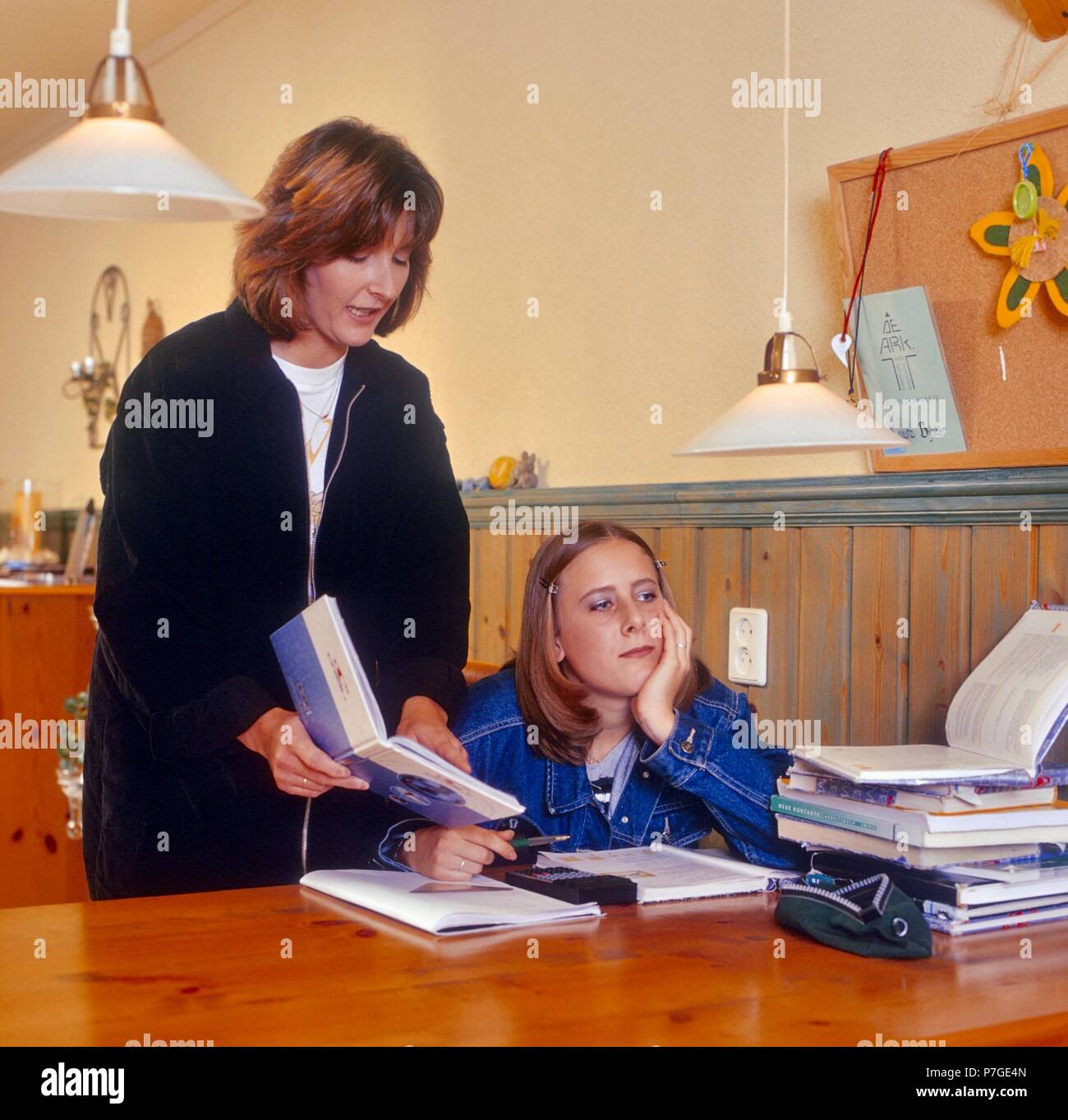 100-001-113 Mother in the 1980s helping her daughter with homework - mother daughter homework at home helpful mum bored uninterested Stock Photo
