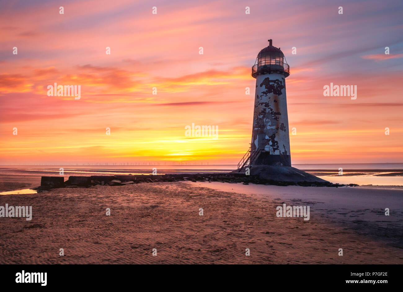 Sunset at Point of Ayr Lighthouse on Talacre Beach, Wales, with colourful sky in the background and low tide Stock Photo