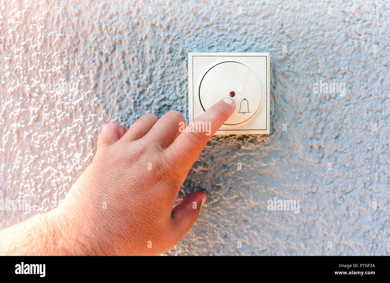hand ringing on doorbell on pvc front door Stock Photo