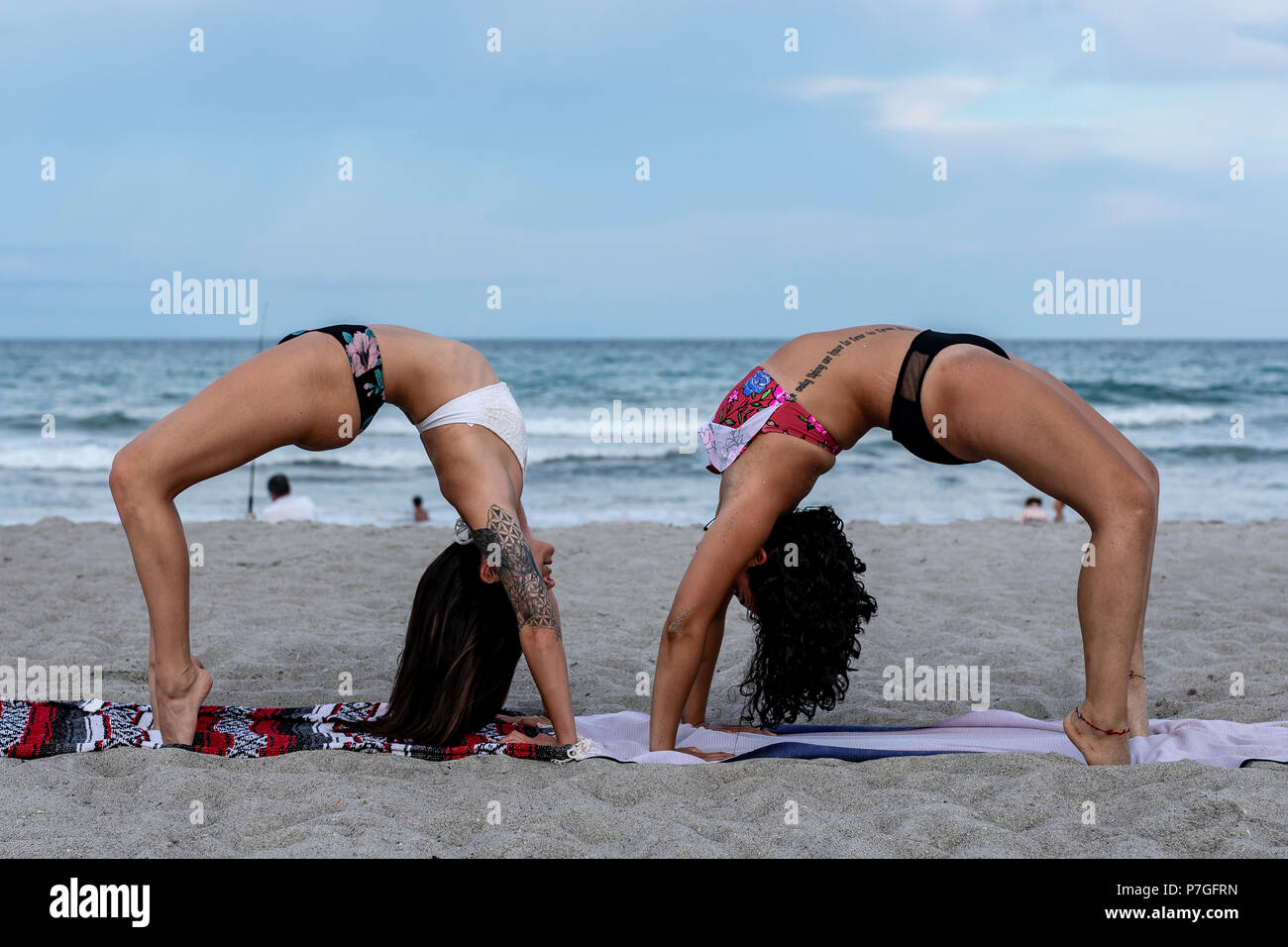twaalf Gelach Doorzichtig Two women wearing bikinis doing a yoga workout on the beach at sunset Stock  Photo - Alamy