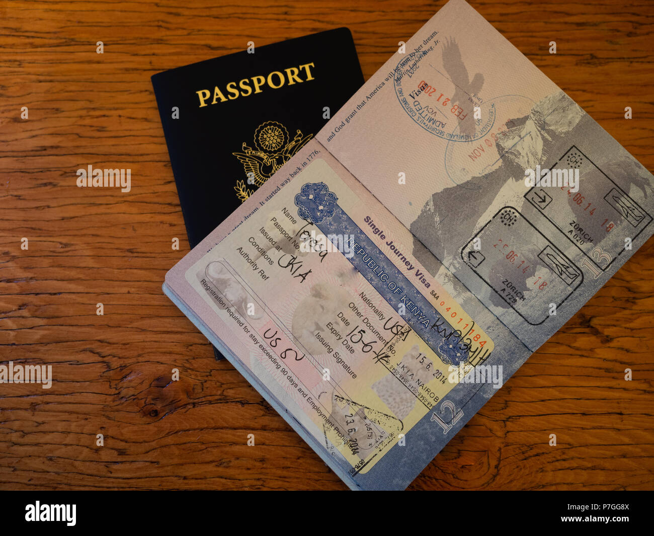 An open US passport showing stamps from Kenya and the Visa required for entry. Photographed on a wooden table. Stock Photo
