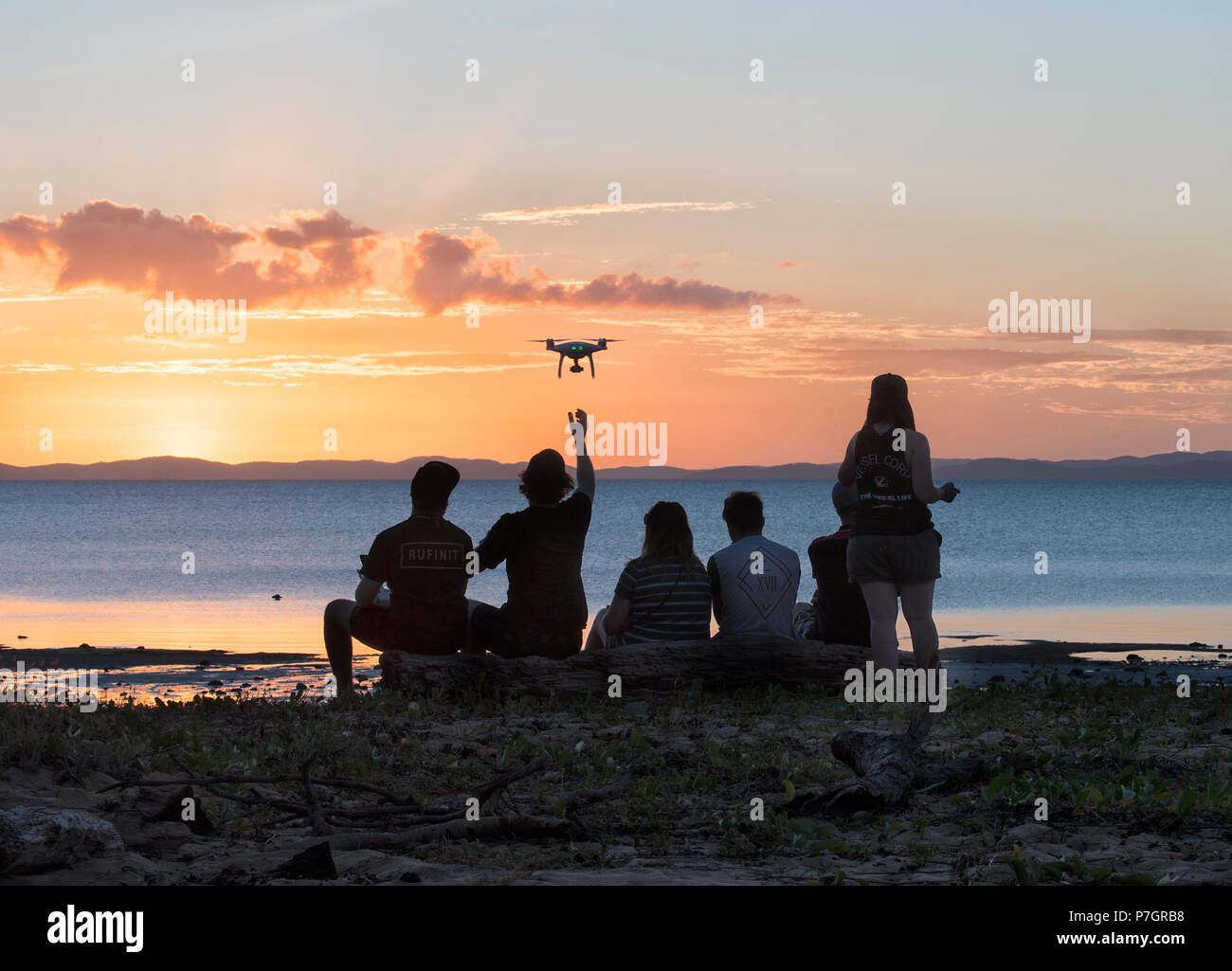 Silhouettes of a group of persons flying a drone at sunset, Loyalty Beach, Seisia, Cape York Peninsula, Far North Queensland, FNQ, QLD, Australia Stock Photo