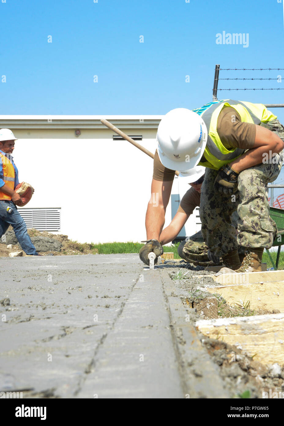 Naples, Italy (September 13, 2016) – Builder 2nd Class Raymond Fenton, assigned to Naval Support Activity Naples Public Works Department, edges wet concrete that will form a slab for a dog kennel on NSA Naples.  Navy Public Works Departments support and maintain facilities and infrastructure on Naval installations worldwide as part of the Naval Facilities Engineering Command (NAVFAC) overall mission. Stock Photo