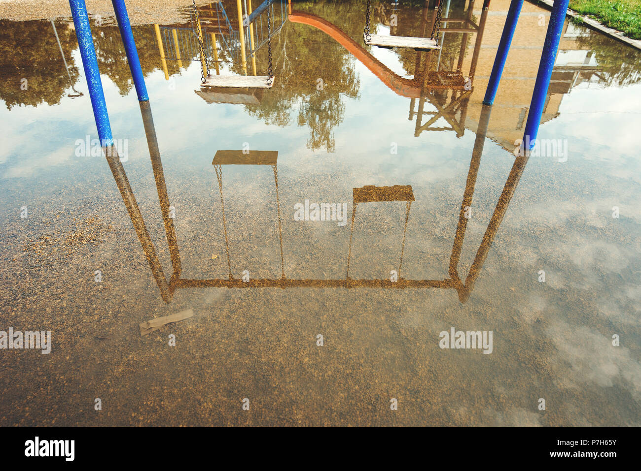 Empty swings on flooded children's playground, reflection on water Stock Photo