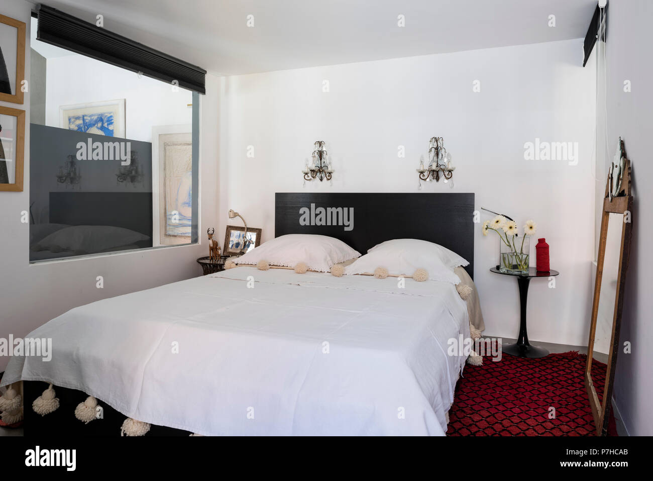 Elegant sleeping area in modern open plan apartment with red morccan reg and antique glass wall sconces Stock Photo