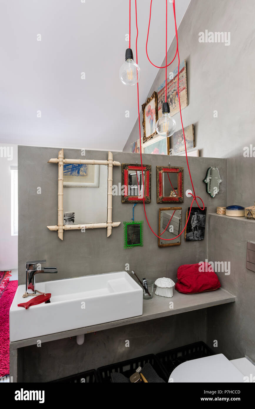 A selection of small vintage mirrors in bathroom of loft apartment with red lighting cable Stock Photo