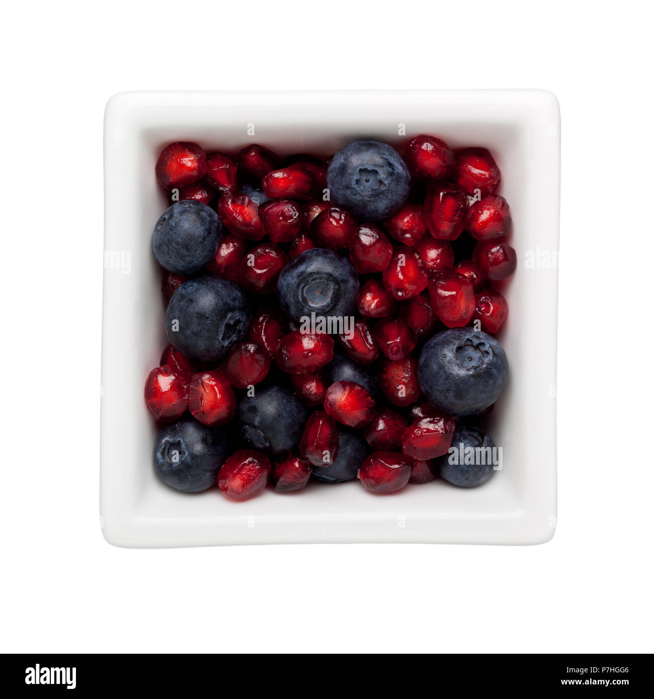 Pomegranate arils and blueberries in a square bowl isolated on white background Stock Photo