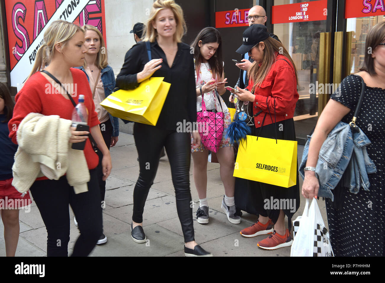 Shoppers and tourists carrying shopping bags walk past the department store Selfridges on Oxford Street in central London. Stock Photo