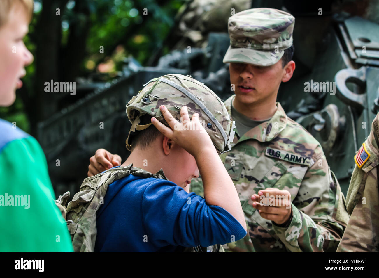 A U.S. Army Soldier with 1st Squadron, 2nd Cavalry Regiment helps a Polish  child try on a Kevlar helmet during a static display with Battle Group  Poland at Giżycko, Poland on June