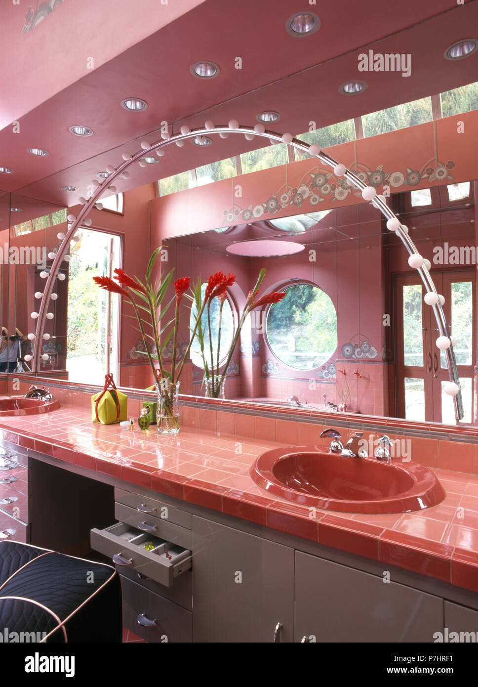 Arched lighting on mirror above basin in tiled vanity unit in pink