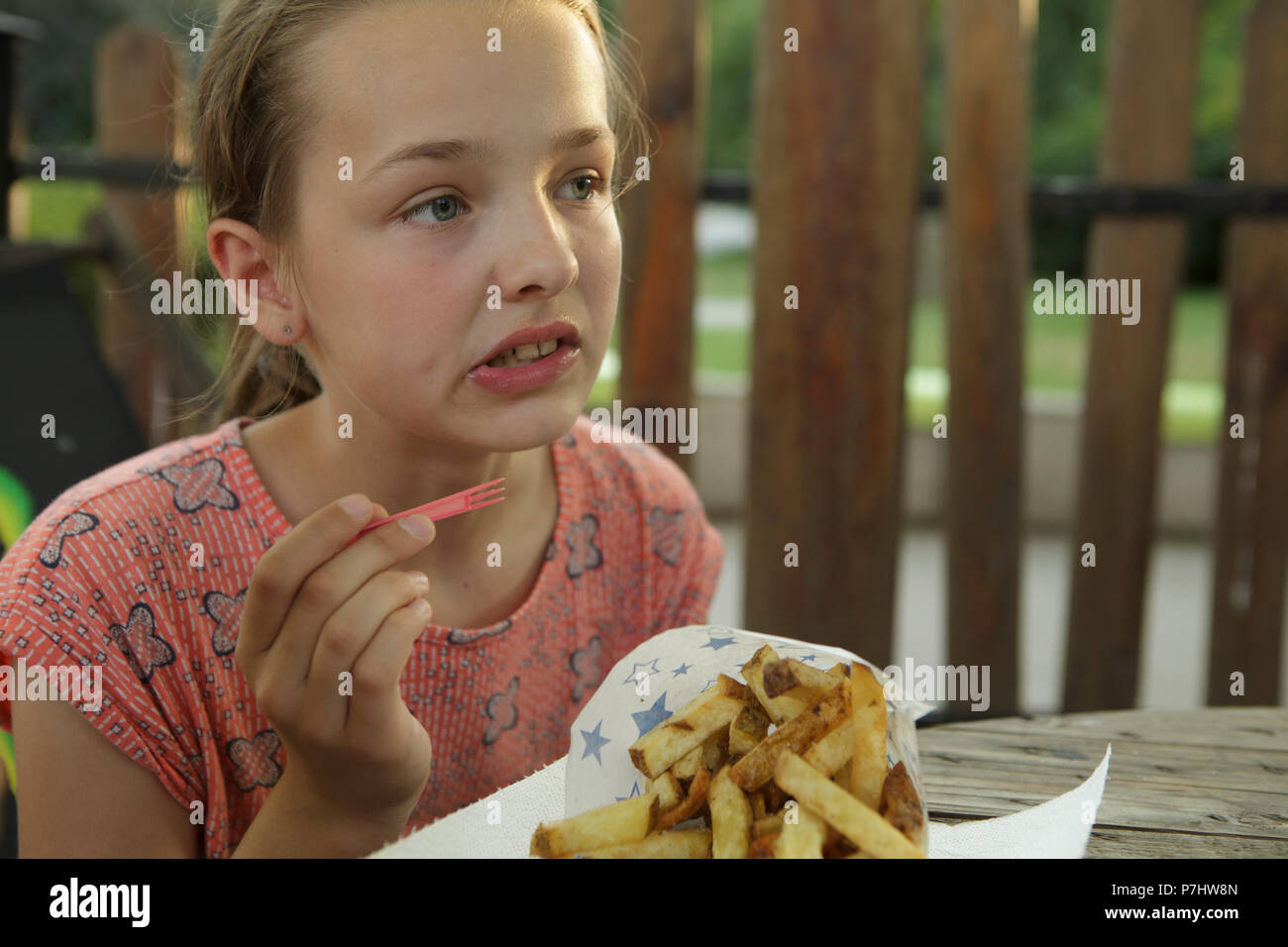 girl eating french frites in park outdoor restaurant Stock Photo