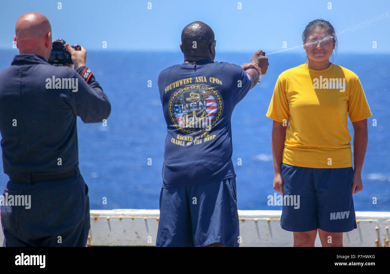 180628-N-GR168-0287 MEDITERRANEAN SEA (June 28 2018) Mass Communication Specialist 2nd Class Lyle Wilkie III, left, takes a photo of Chief Master-at-Arms Bernard Hyppolite spraying Ensign Genelle Arandia, from Gainesville, Florida, with oleoresin capsicum spray during security reaction force training aboard the San Antonio-class amphibious transport dock ship USS New York (LPD 21) June 28, 2018. New York, homeported in Mayport, Florida, is conducting naval operations in the U.S. 6th Fleet area of operations in support of U.S. national security interest in Europe and Africa.  (U.S. Navy photo b Stock Photo
