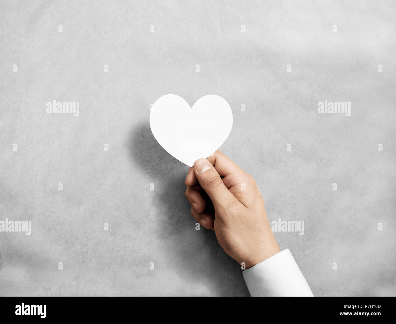 Hand holding blank white valentine's card mockup. Arm hold paper love invitation, design mock up. Holiday greeting postcard presentation. Person showi Stock Photo