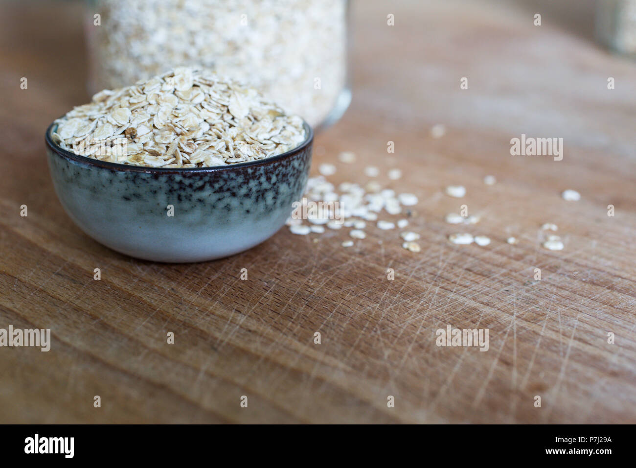 clean eating with rolled oats for porridge in heap in ceramic bowl on wooden table Stock Photo