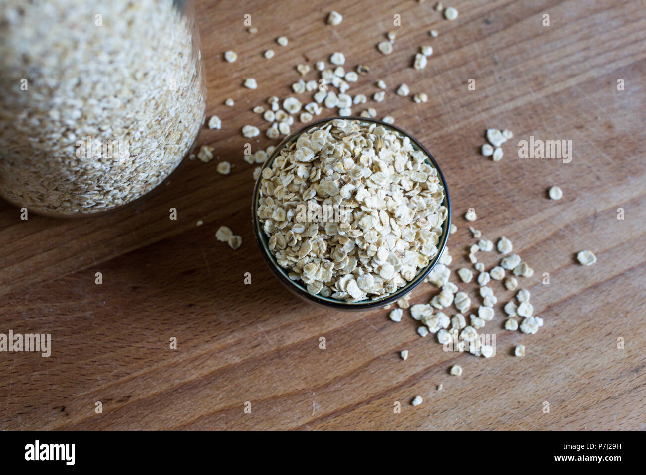 organic natural oats for porridge in heap in ceramic bowl on wooden table Stock Photo