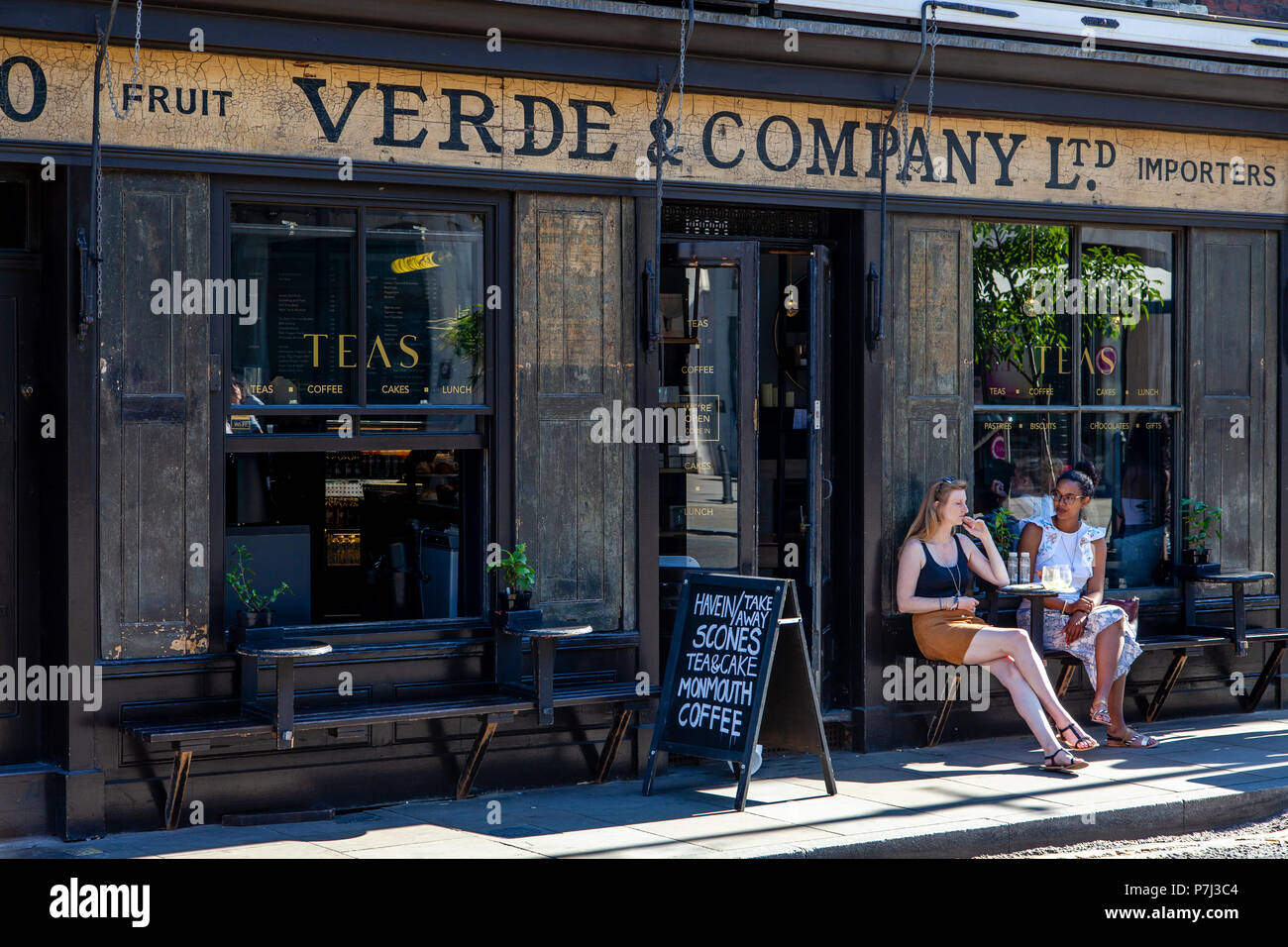 Two Young Women Sitting Outside Verde & Company Cafe, Spitalfields, London, England Stock Photo