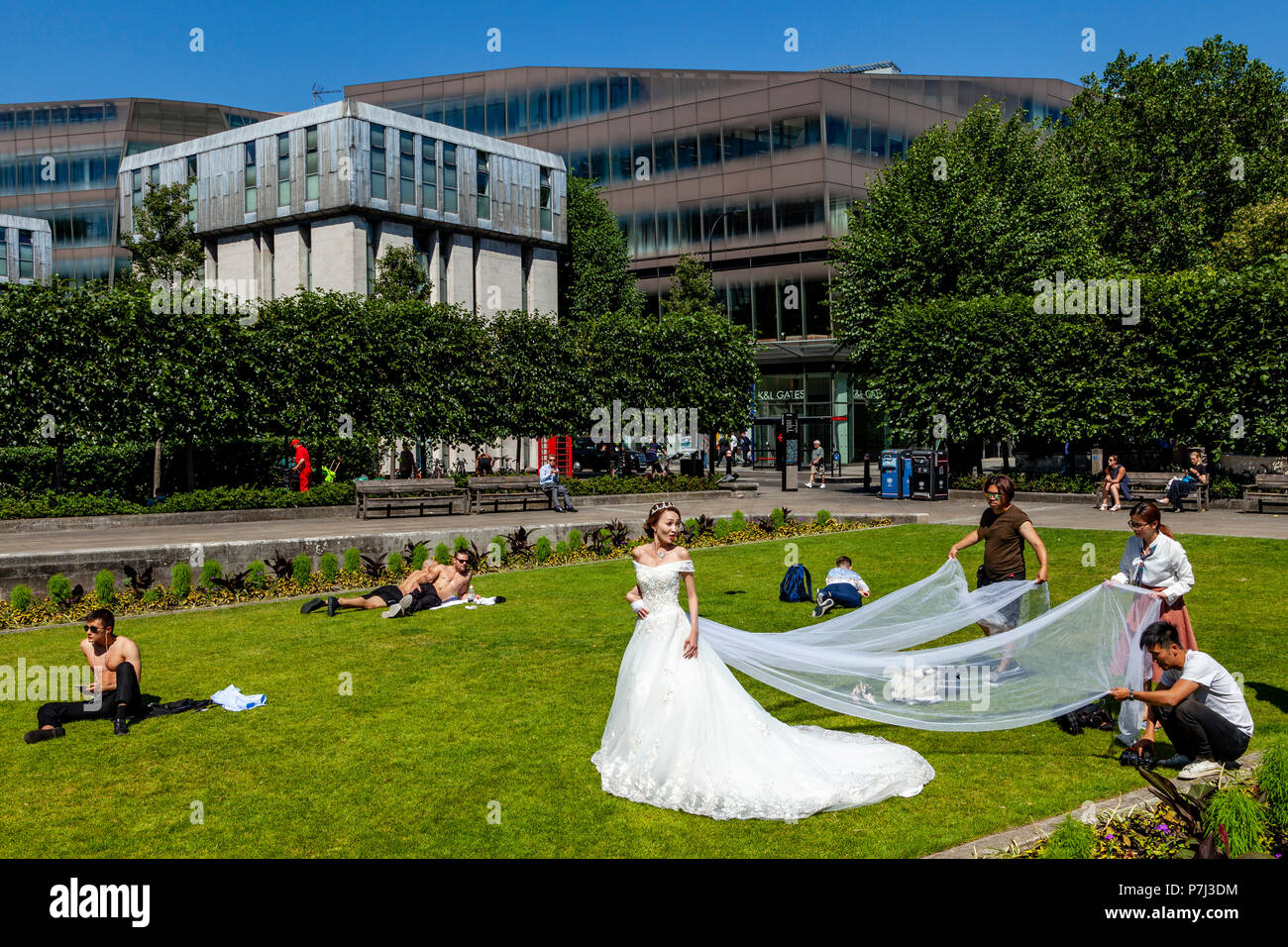 A Visiting Bride From Hong Kong Poses For Wedding Photography On The Lawns Outside St Paul’s Cathedral, London, England Stock Photo