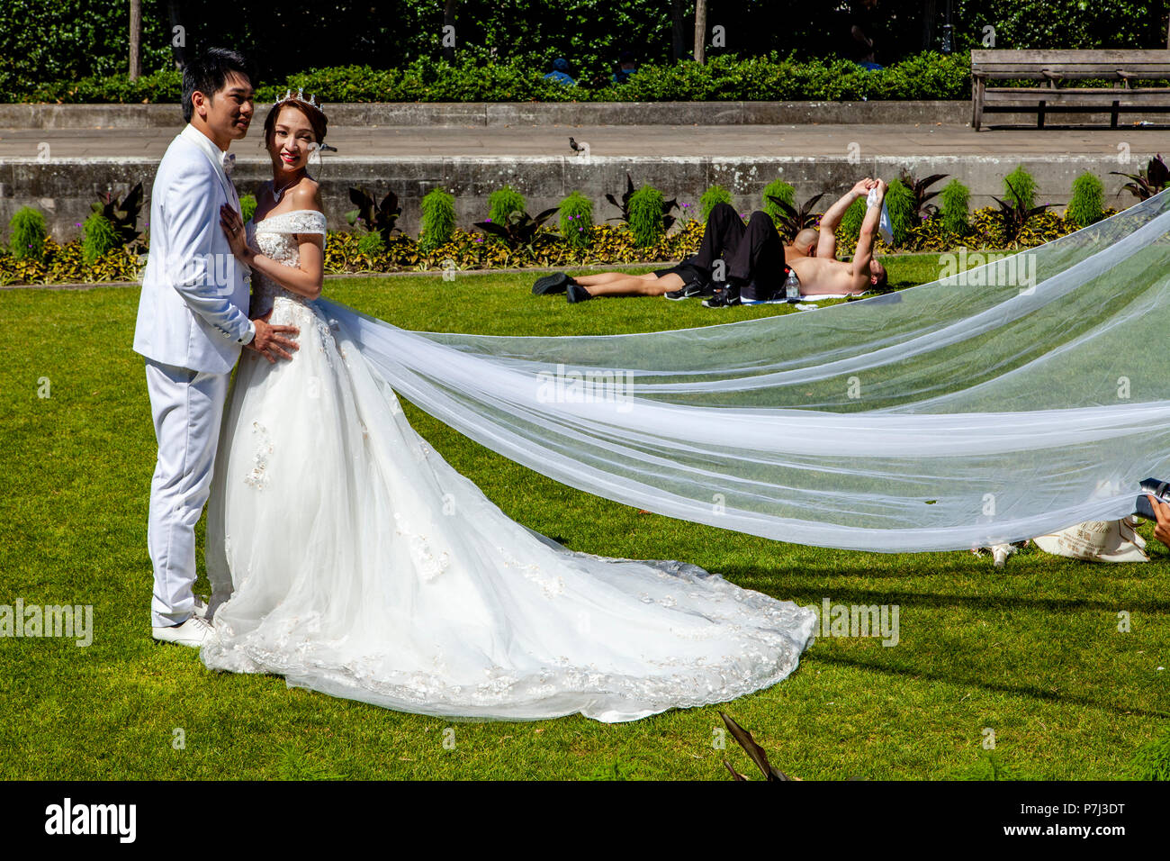A Visiting Bride and Groom From Hong Kong Pose For Wedding Photography On The Lawns Outside St Paul’s Cathedral, London, England Stock Photo