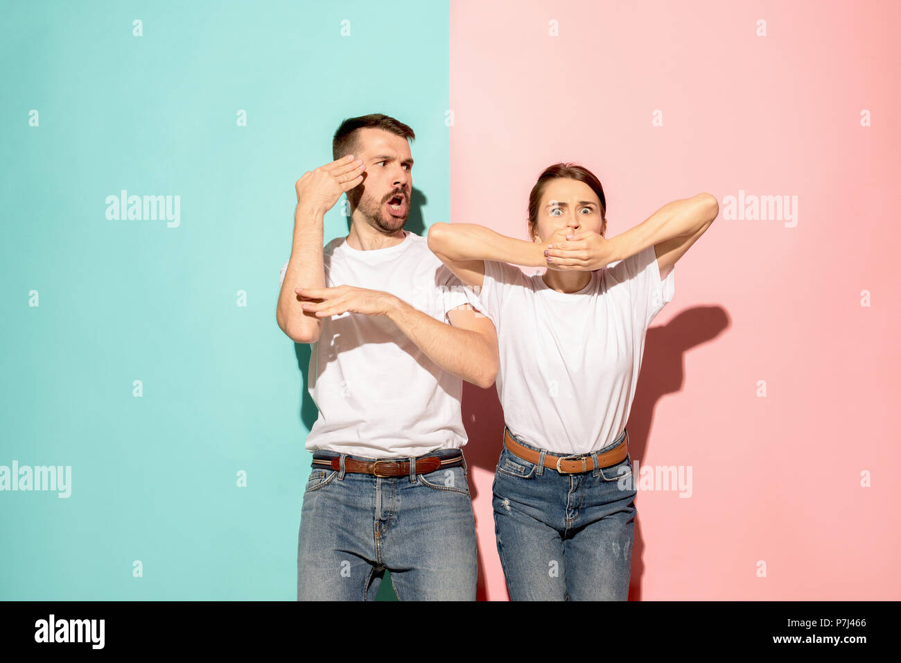 Closeup portrait of young couple, man, woman. TV fan concept on pink and blue background. Emotion contrasts Stock Photo