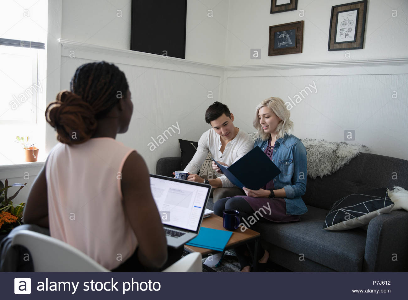 Financial advisor consulting with young couple in living room Stock Photo