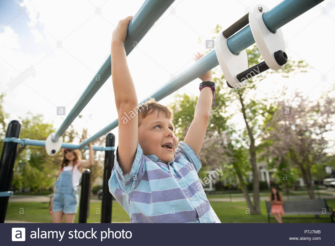 Playful boy swinging from monkey bars at playground Stock Photo Alamy
