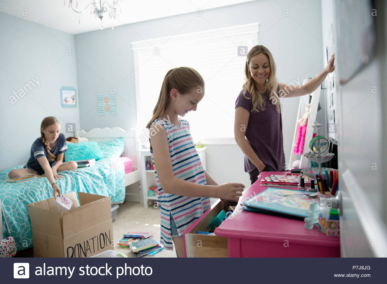 Mother and daughters organizing bedroom, donating Stock Photo