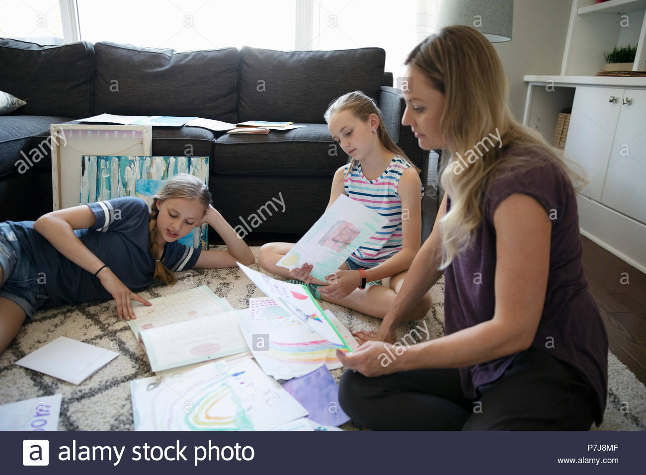Mother and daughters doing art project on living room floor Stock Photo