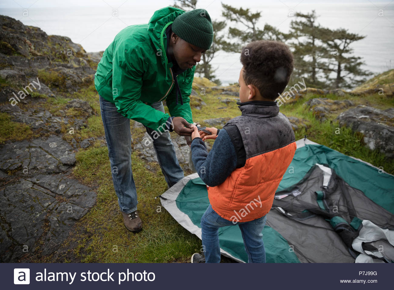 Father and son preparing tent at campsite Stock Photo