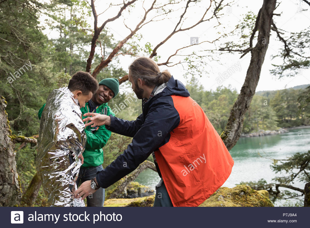 Trail guide wrapping thermal blanket around boy hiking in woods Stock
