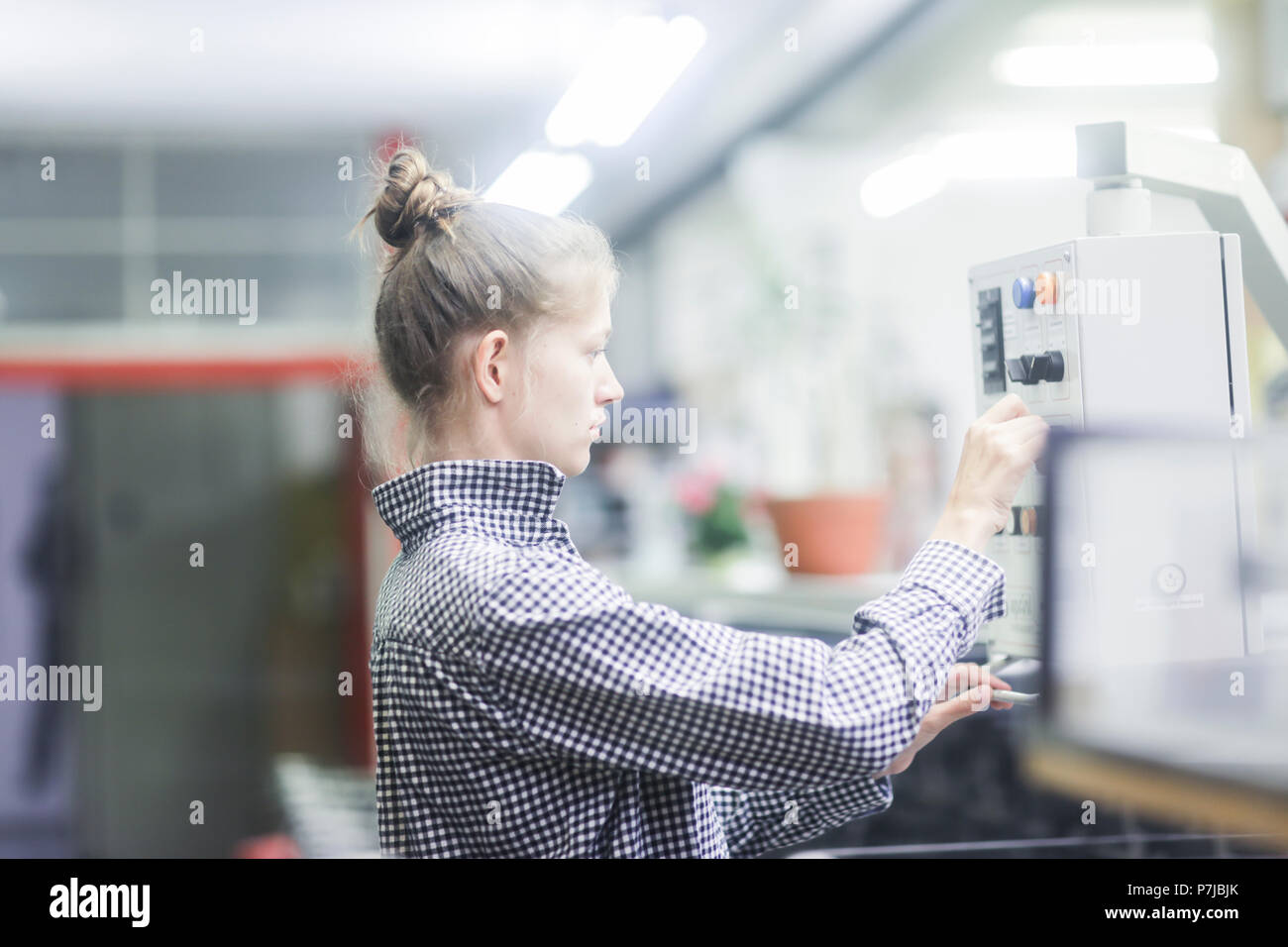 Woman operating a machine in a factory Stock Photo