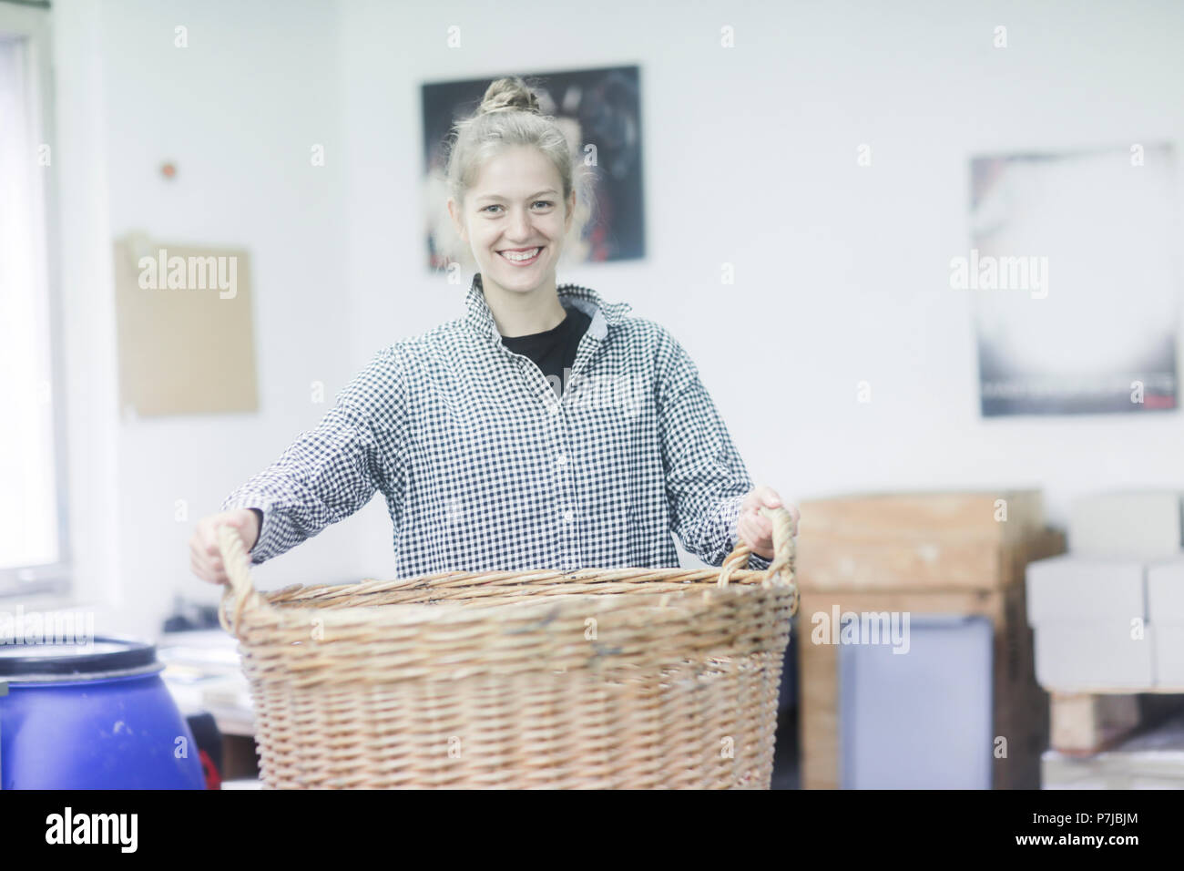 Woman standing in a workshop carrying a basket Stock Photo