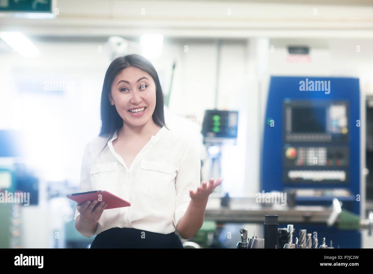 Smiling female engineer standing in a workshop holding a digital tablet Stock Photo