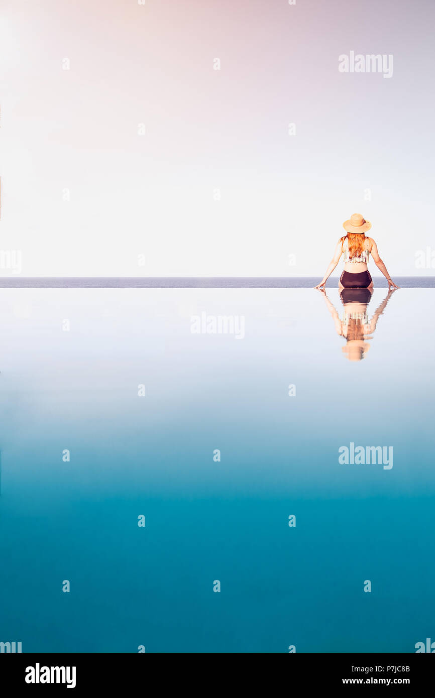 Woman sitting on the edge of an infinity pool Stock Photo - Alamy