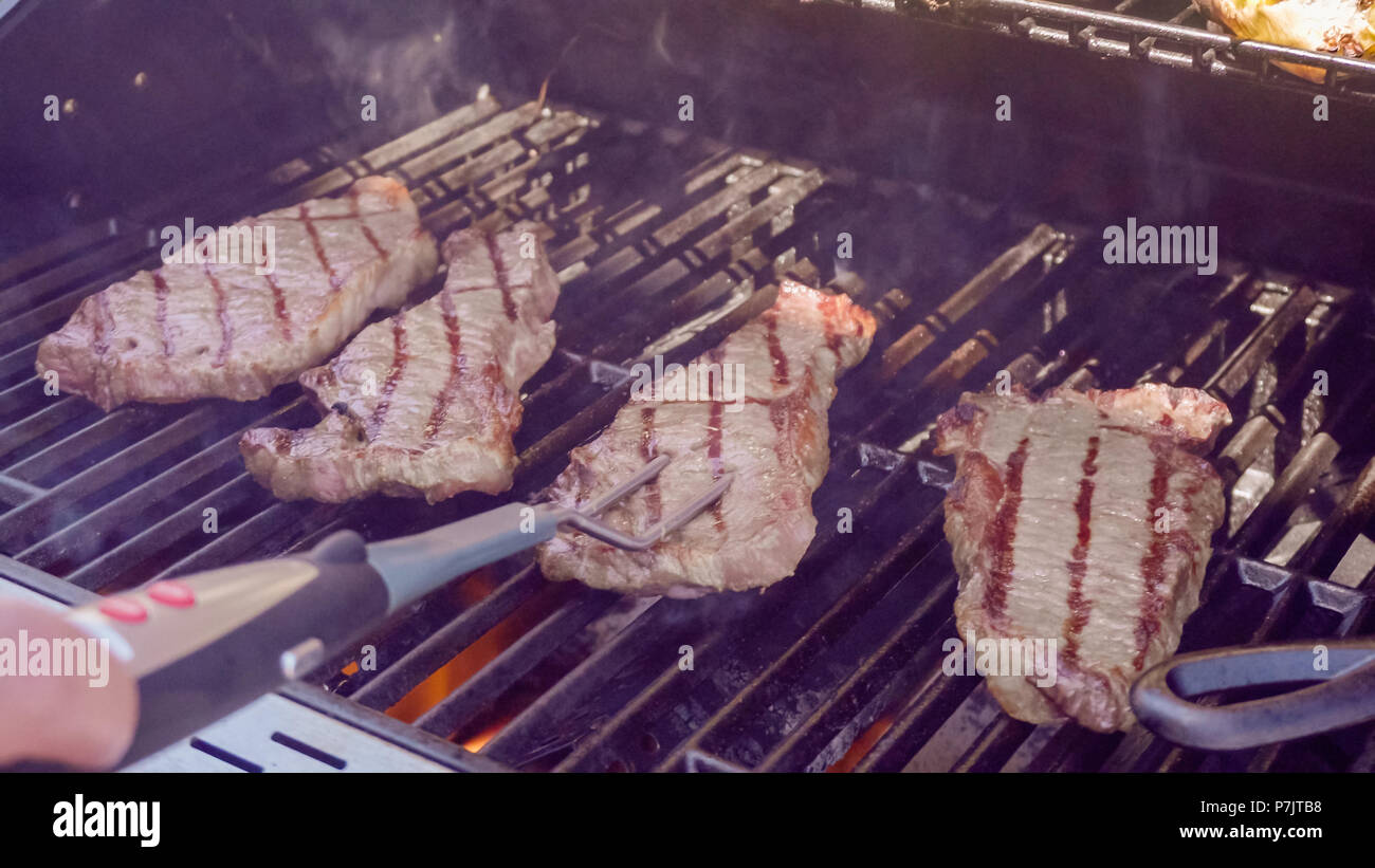 Step by step. Grilling New York strip steak on outdoor gas grill Stock