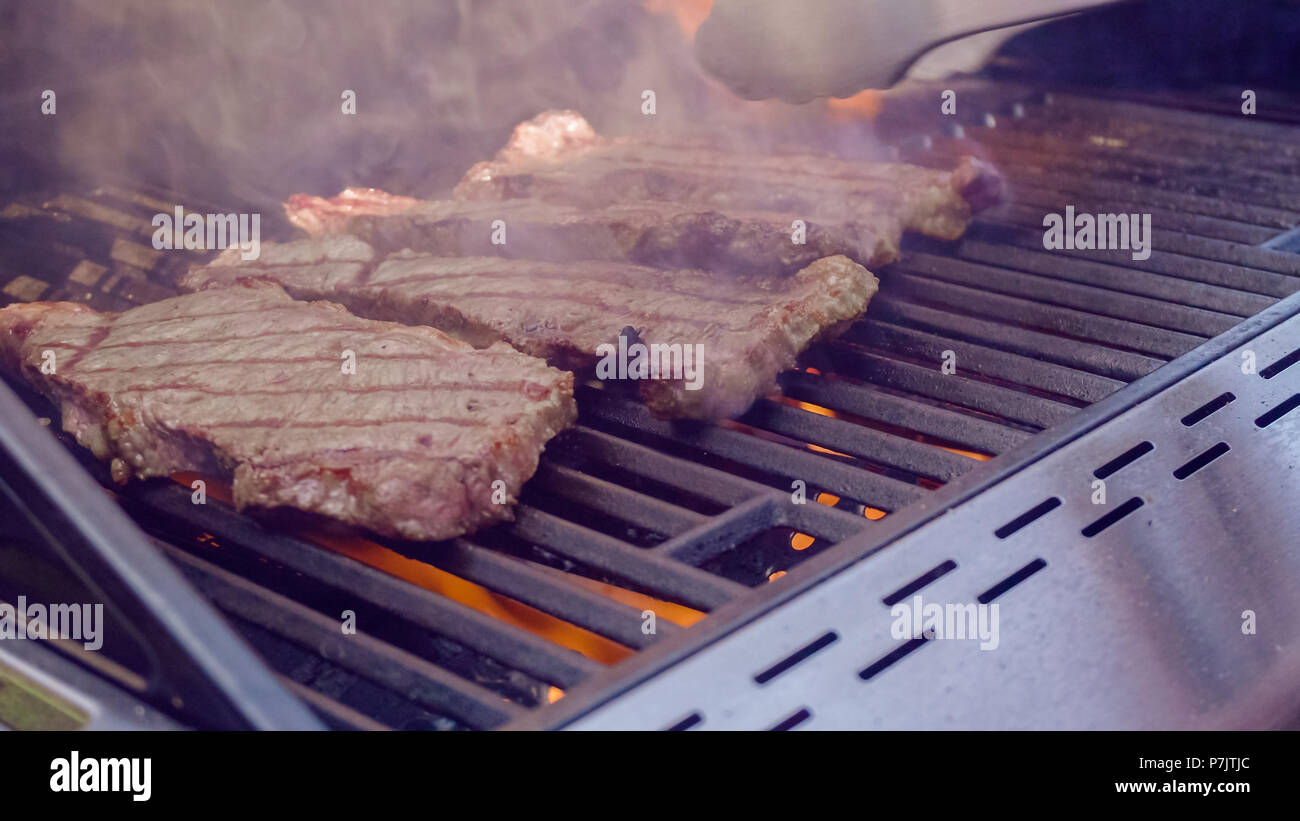 Step by step. Grilling New York strip steak on outdoor gas grill Stock