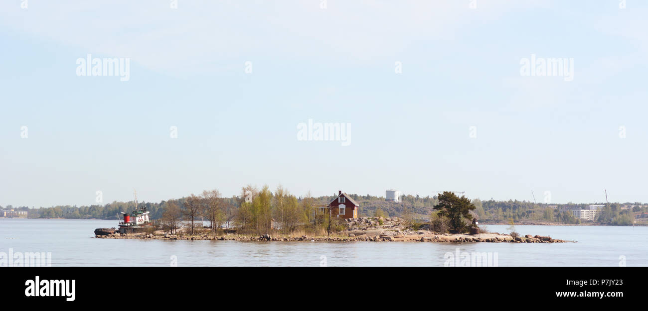 HELSINKI, FINLAND - May 14, 2018: Boat moored on Katajanokanluoto island with small dwellings visible through the trees - seen from the ferry between  Stock Photo