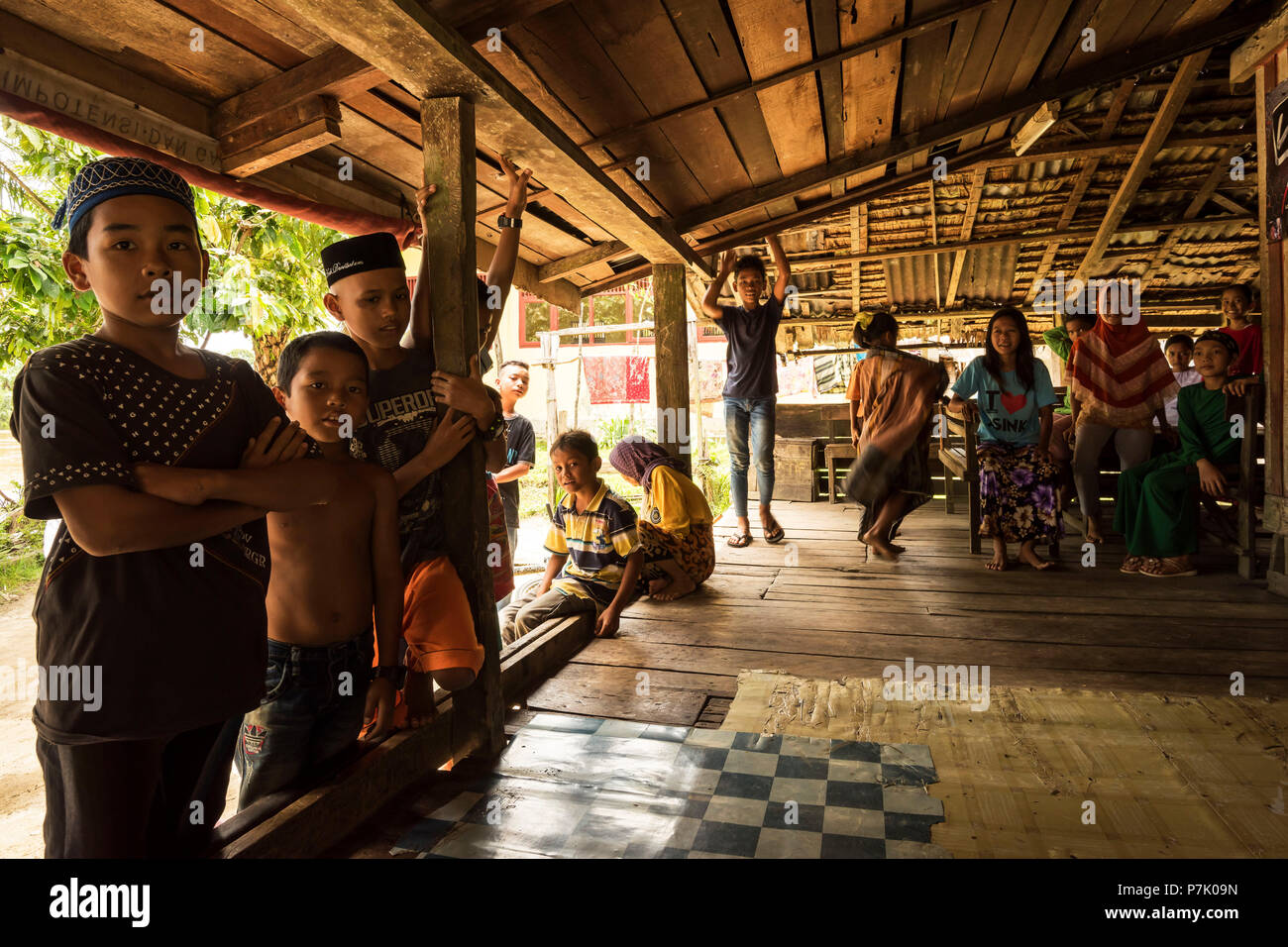 Children standing and sitting under a canopy and watching us Stock Photo