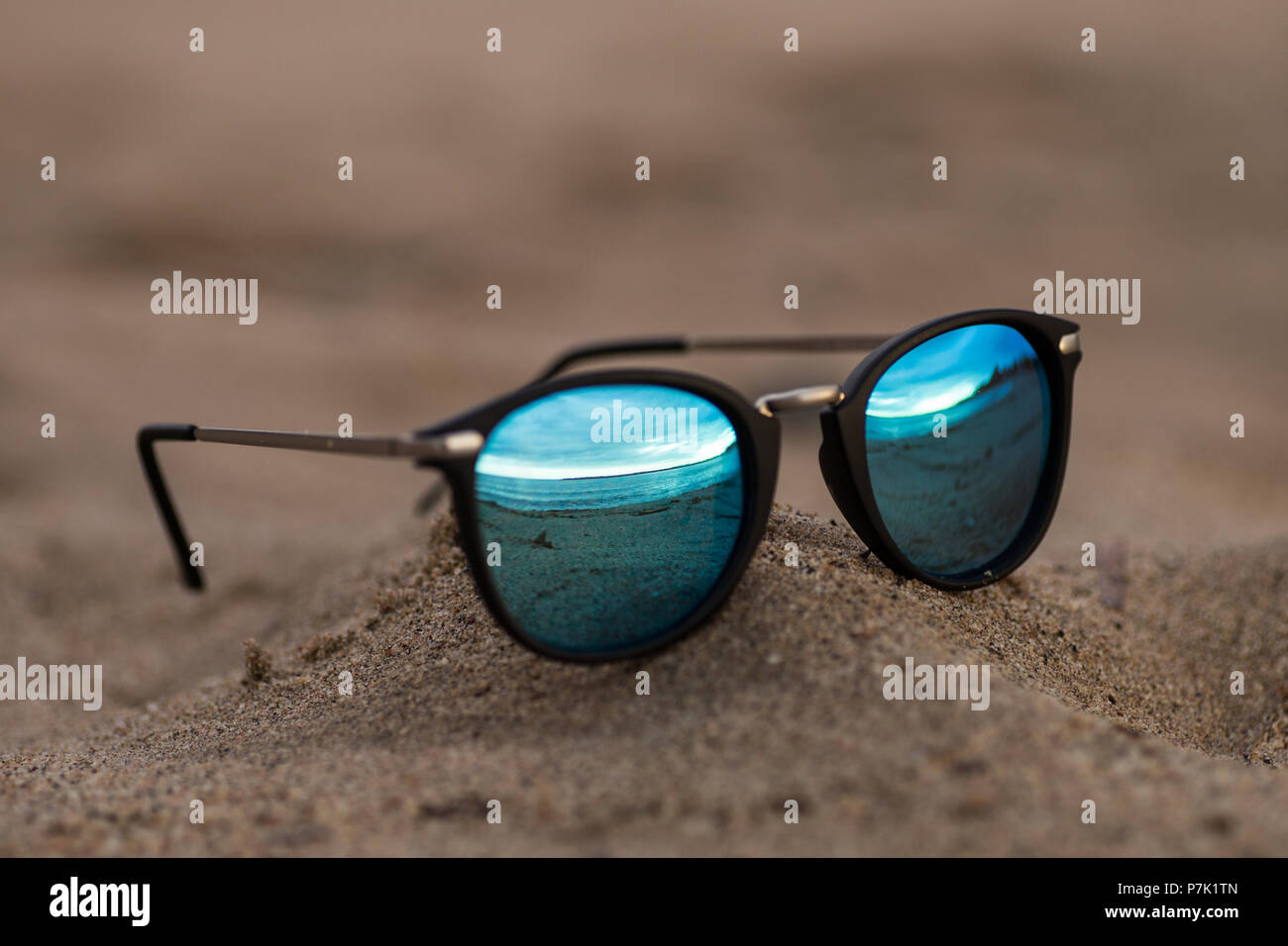 Round sunglasses with mirror reflection on the sand on sunny summer beach.  Travel vacations concept Stock Photo - Alamy