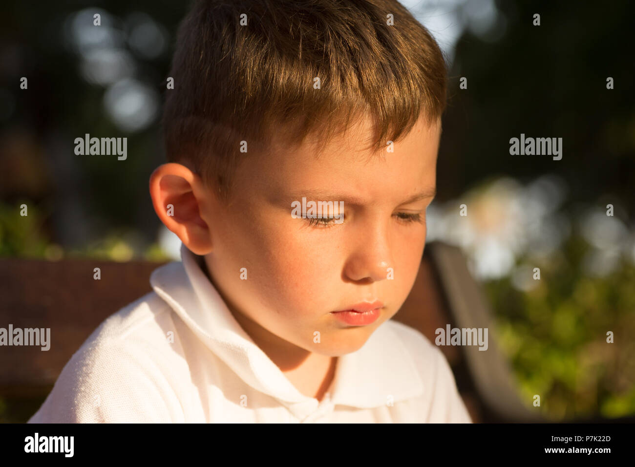 Beautiful little brunet hair boy, has serious face, happy eyes. Child portrait. Summer time. Close up. Stock Photo