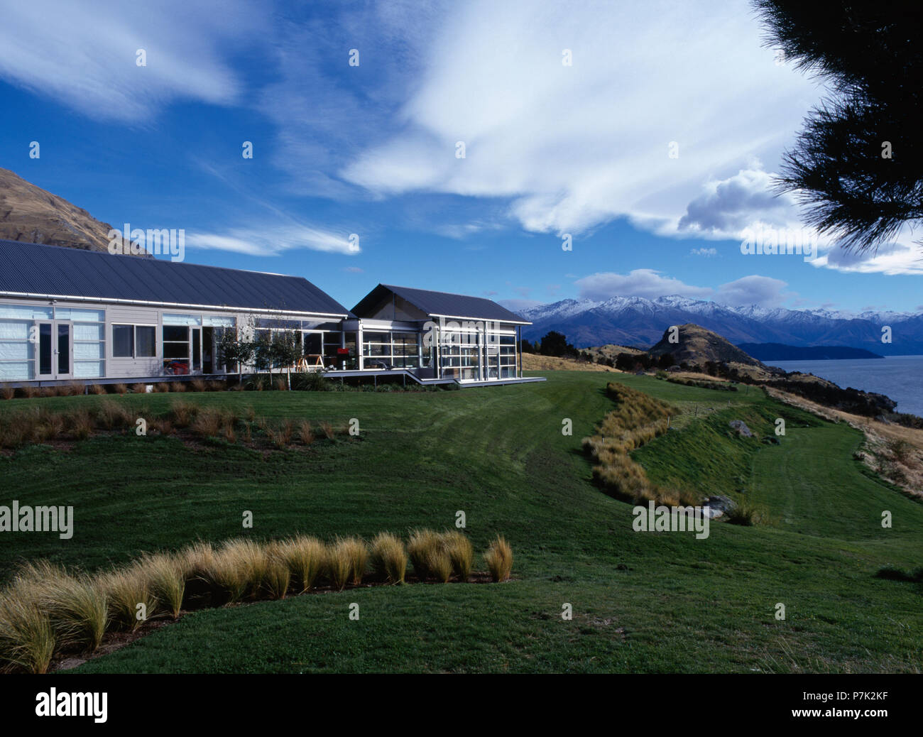 Modern single storey house beside the ocean in New Zealand with mountains in the background Stock Photo