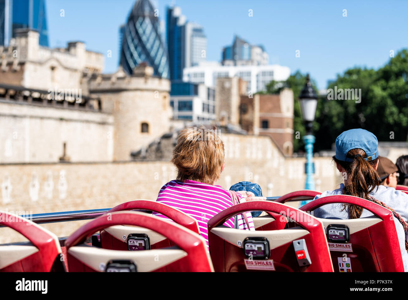 London, UK - June 22, 2018: Back of women tourists looking at city cityscape view, tower fortifications wall buildings on street road double decker re Stock Photo