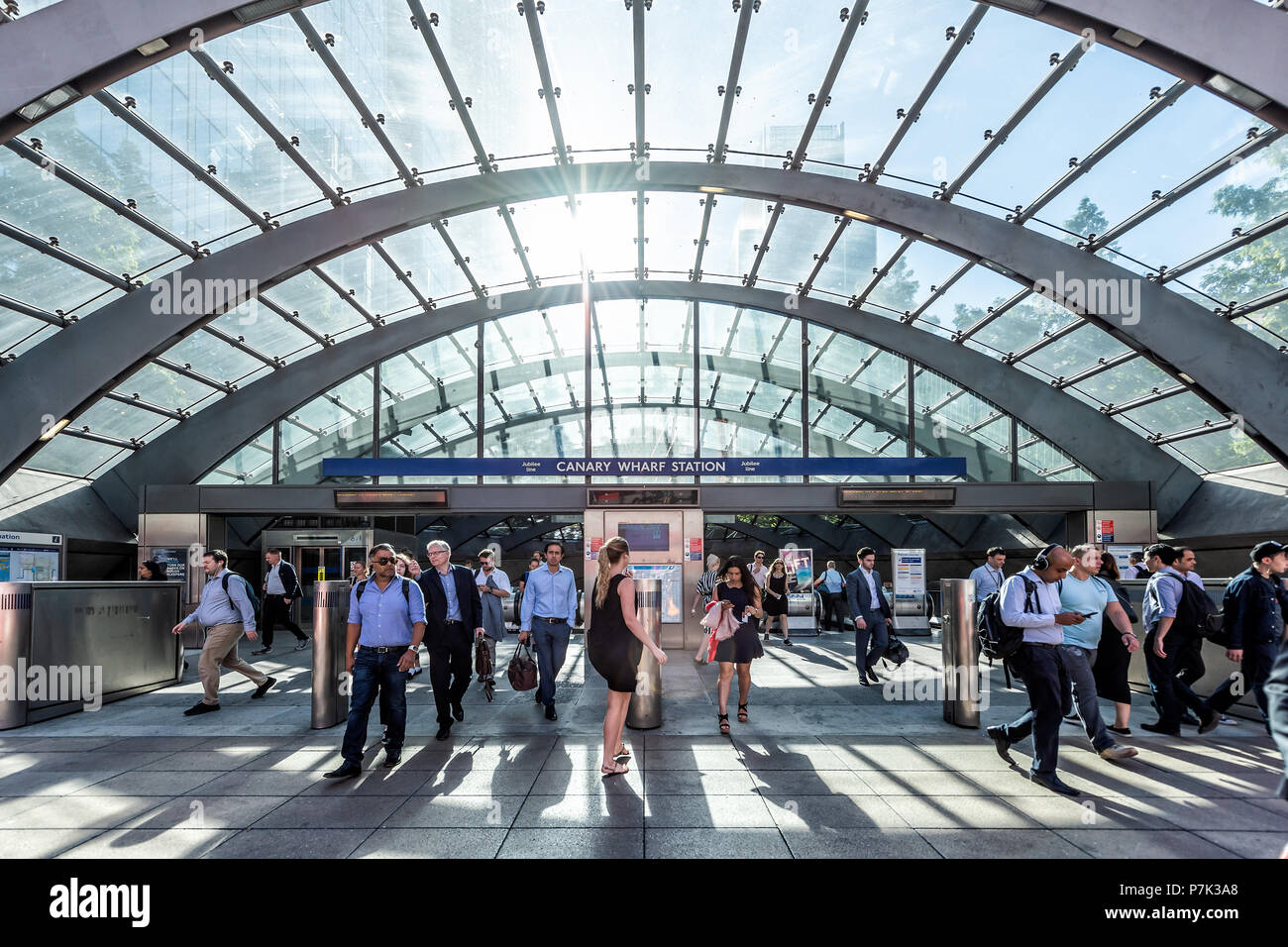 London, UK - June 26, 2018: People crowd commuters in front of outside Underground tube metro entrance during morning commute in Canary Wharf with mod Stock Photo