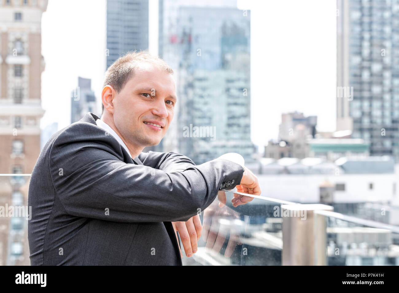 Handsome, attractive young side profile businessman closeup face portrait standing in suit, tie, looking at New York City cityscape skyline in Manhatt Stock Photo