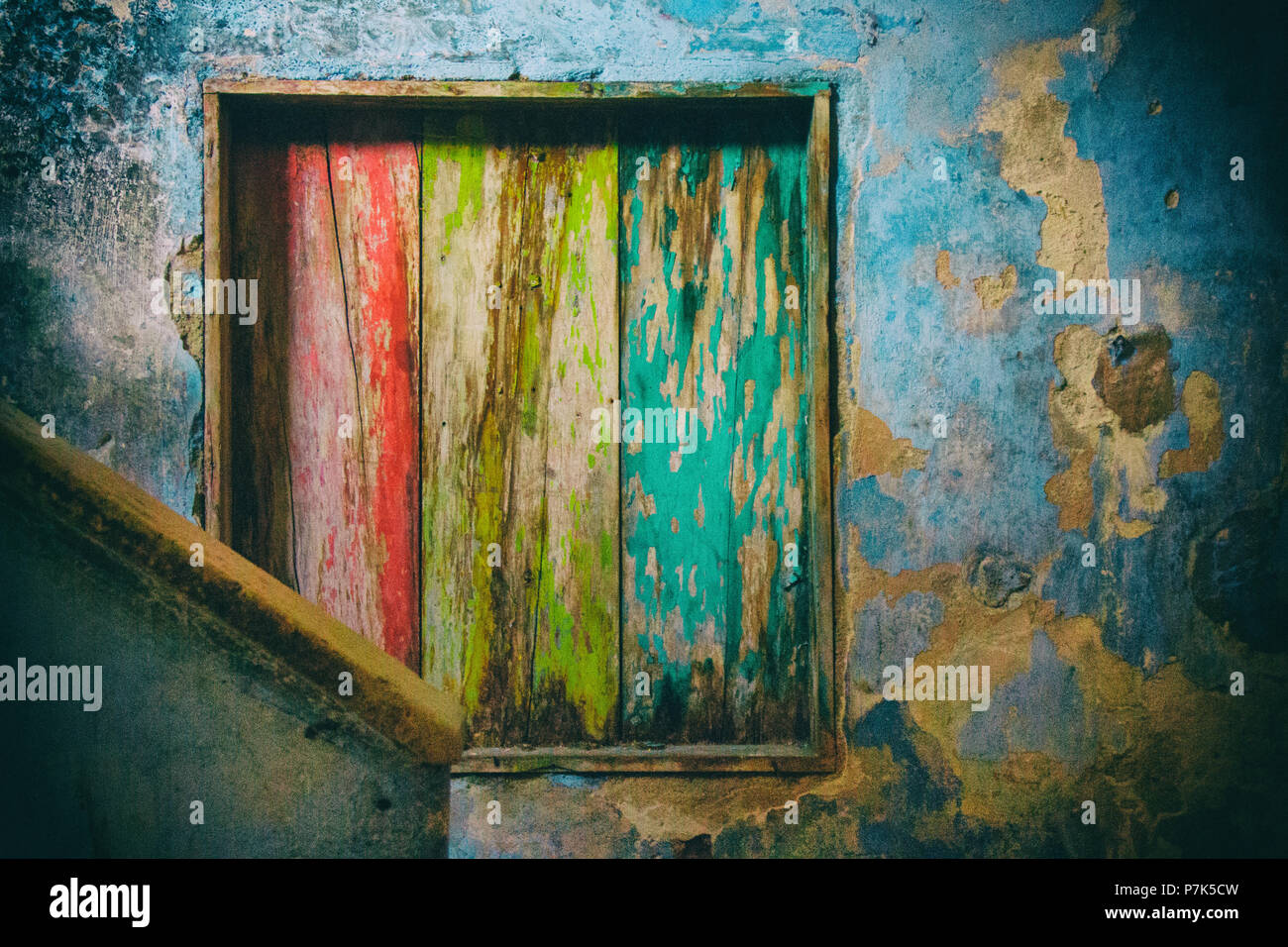 In a decayed ambient with cracked blue walls a wood internal window is ...