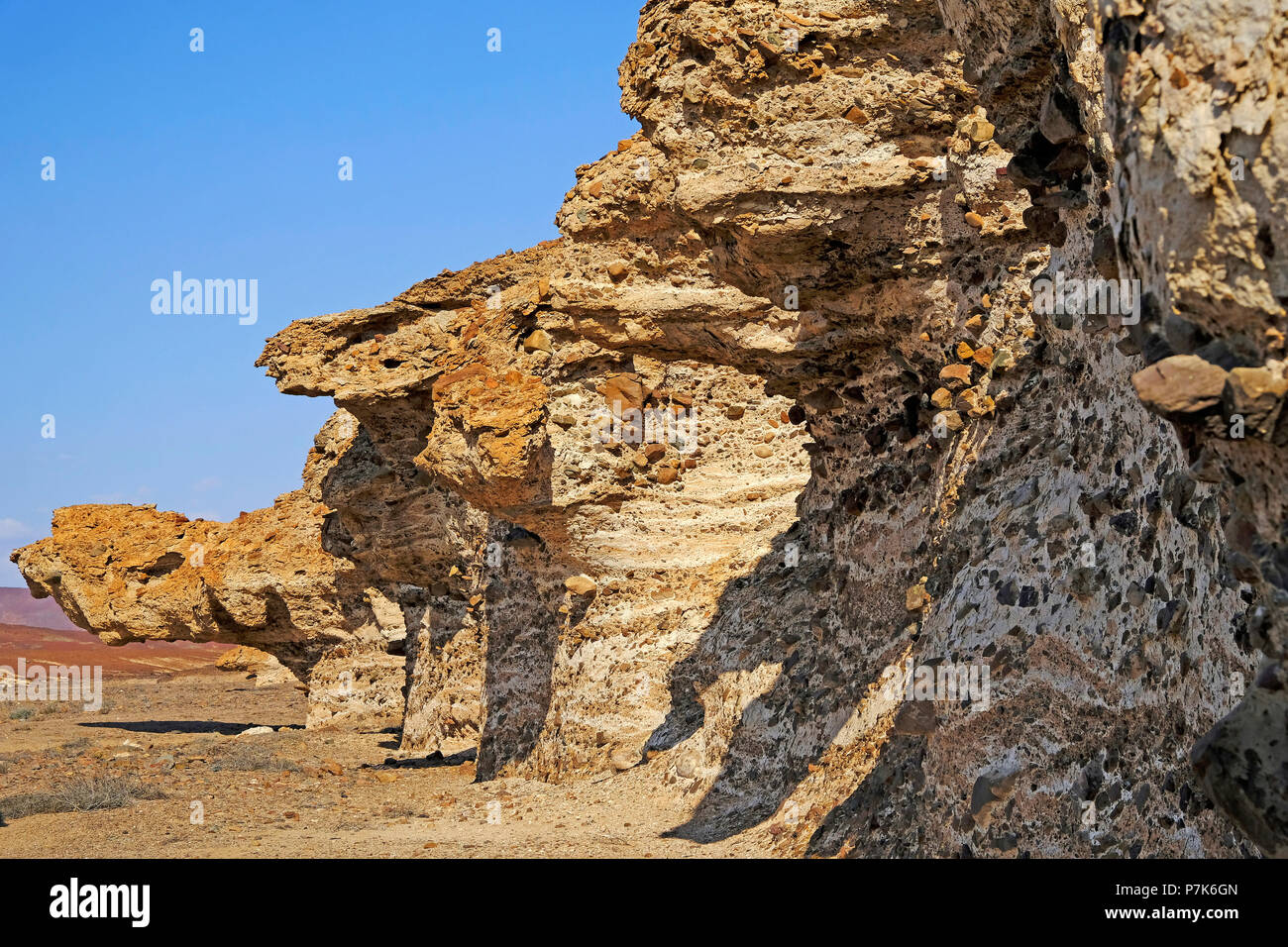 under-washed, overhanging terraces and steep bank with coloured inclusions on a tributary of the dry river Messum in the Dorob National Park in Namibia Stock Photo