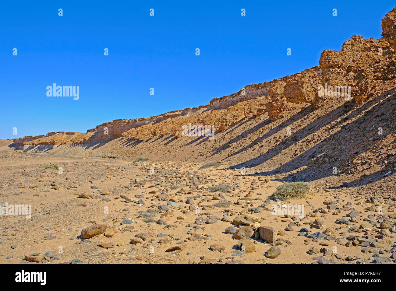 under-washed, overhanging terraces and steep bank with coloured inclusions on the dry river Messum in the Dorob National Park in Namibia Stock Photo